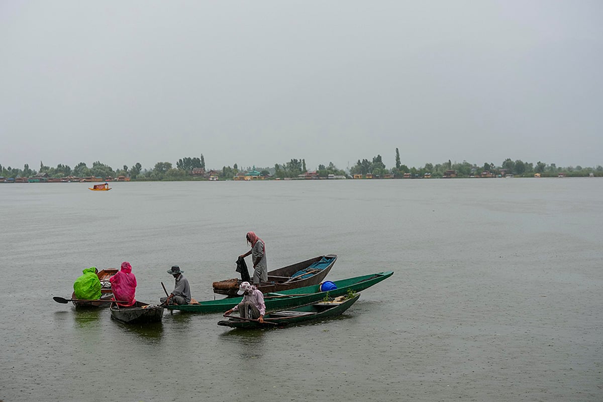 Weather: Boatmen wait during Rain in Srinagar